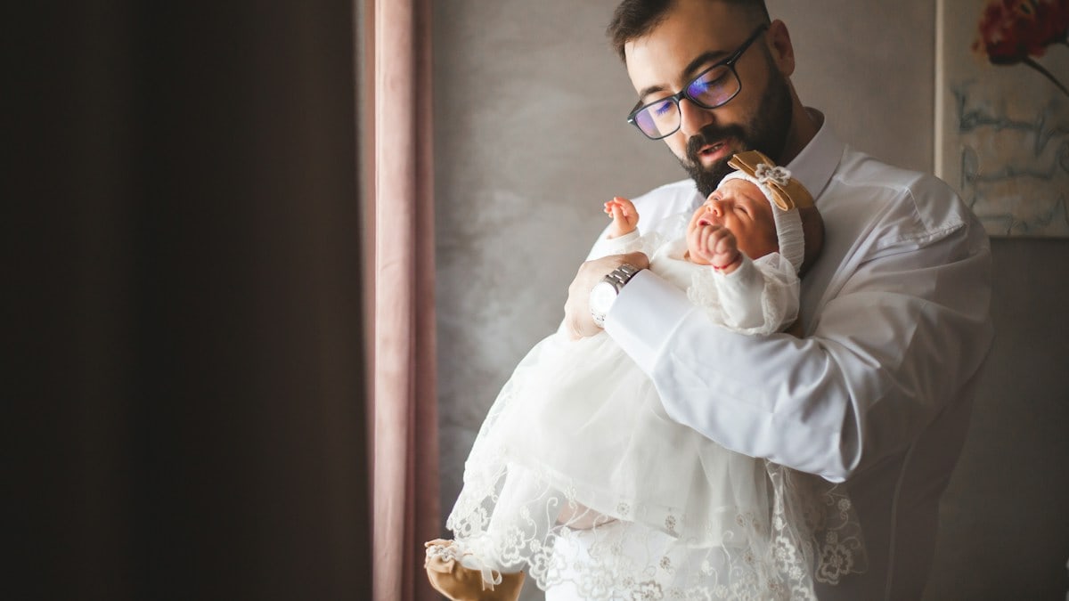 Father holding his young baby girl, and looking at her.